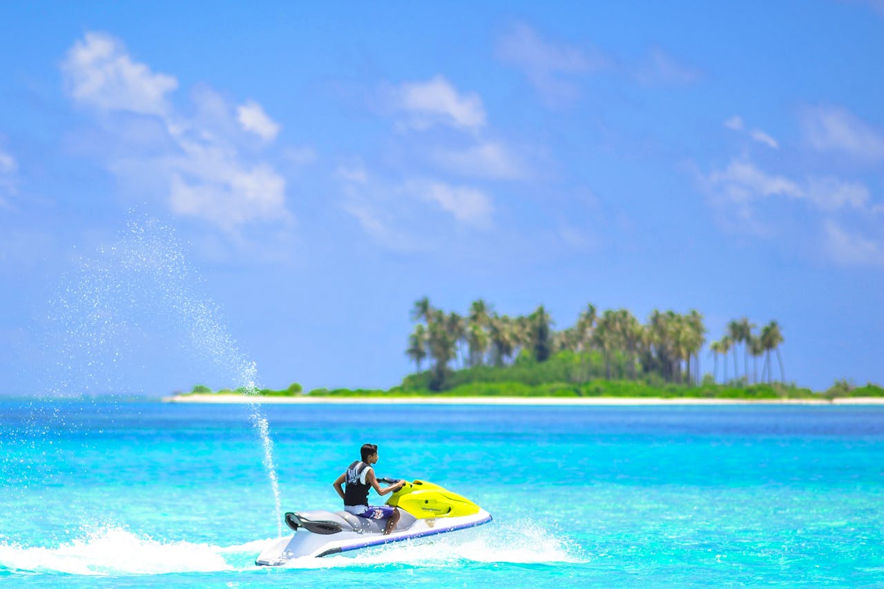 Vibrant jet ski adventure near a picturesque island in the tropical Maldives with clear blue waters and palm trees.