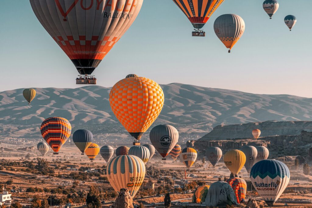 Colorful hot air balloons soaring over Cappadocia's unique landscape in Türkiye.