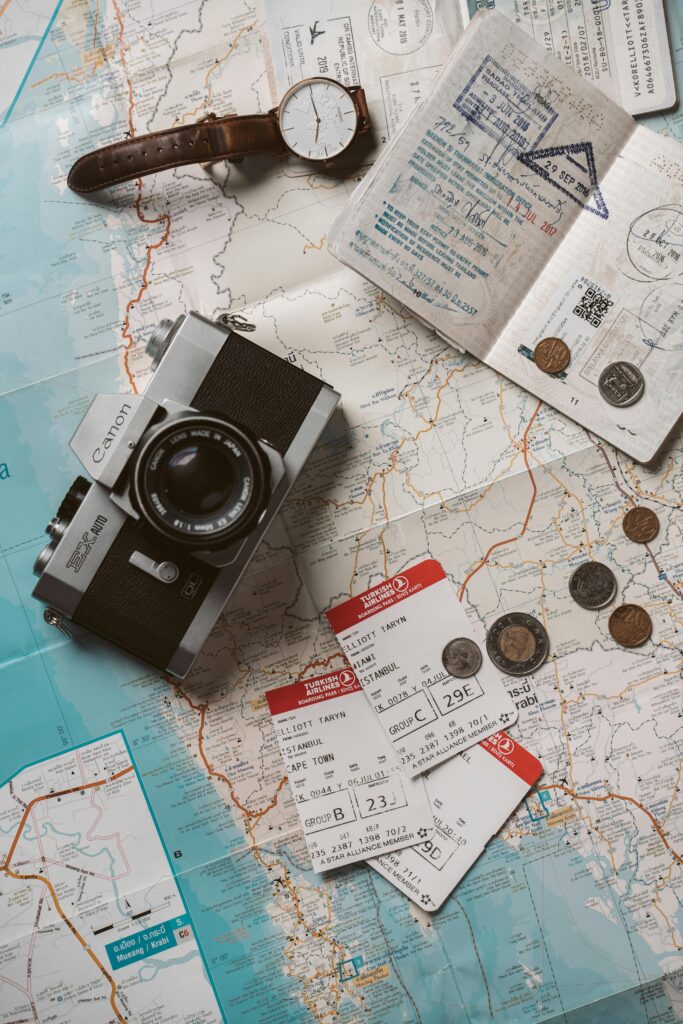 Flat lay travel essentials including passports, tickets, and a vintage camera on a world map.